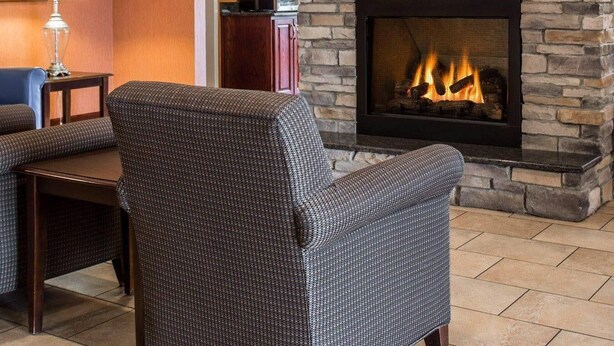 A living room with a stone fireplace, a sofa, a table, and a lamp. - Comfort Inn & Suites Lumberton Central I-95 (Lumberton)