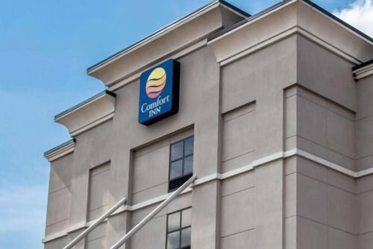 Un edificio con el letrero de Comfort Inn, que presenta un estilo arquitectónico moderno con techo plano y varias ventanas.