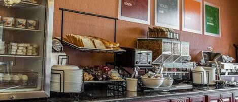 A breakfast bar with various food items, a coffee machine, and a toaster.