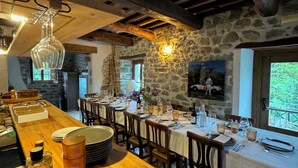 A rustic dining area with stone walls, wooden beams, and a long wooden table set for a meal. - Bio Agriturismo il Vigno (Caprese Michelangelo)