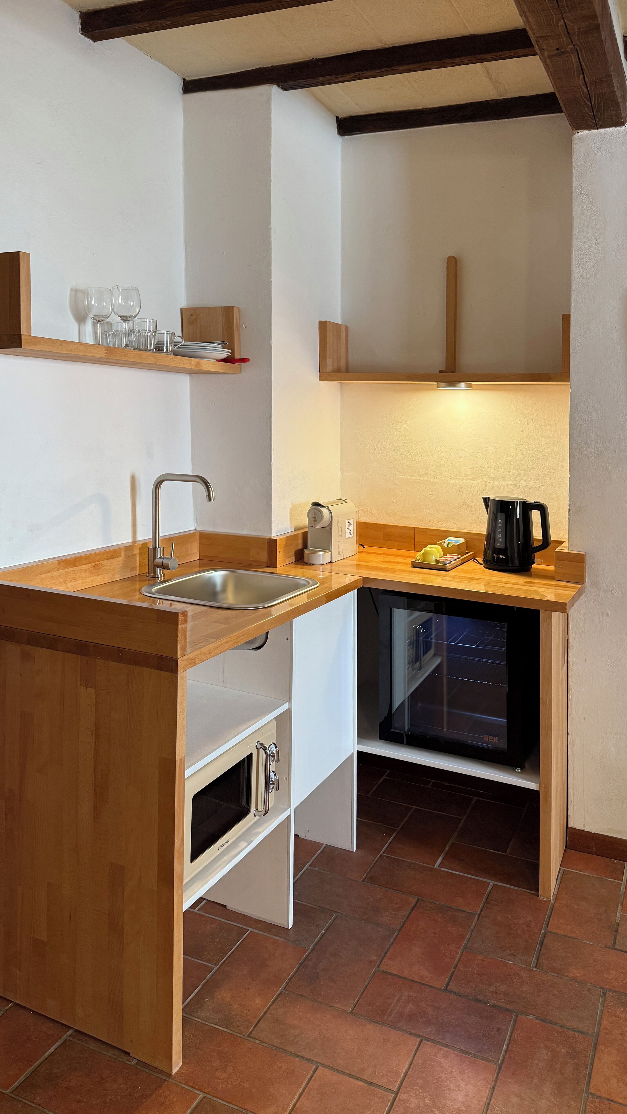 A compact kitchen with a wooden countertop, a built-in oven, a coffee maker, and a sink.