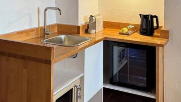 A compact kitchen with a wooden countertop, a built-in oven, a coffee maker, and a sink.