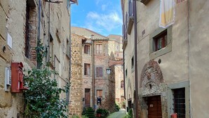 A narrow alleyway with stone buildings, potted plants, and a red pole. - Bio Agriturismo il Vigno (Caprese Michelangelo)