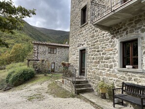 Guests can enjoy a traditional balcony with metal railings, surrounded by a serene natural landscape and a view of the forested hill.