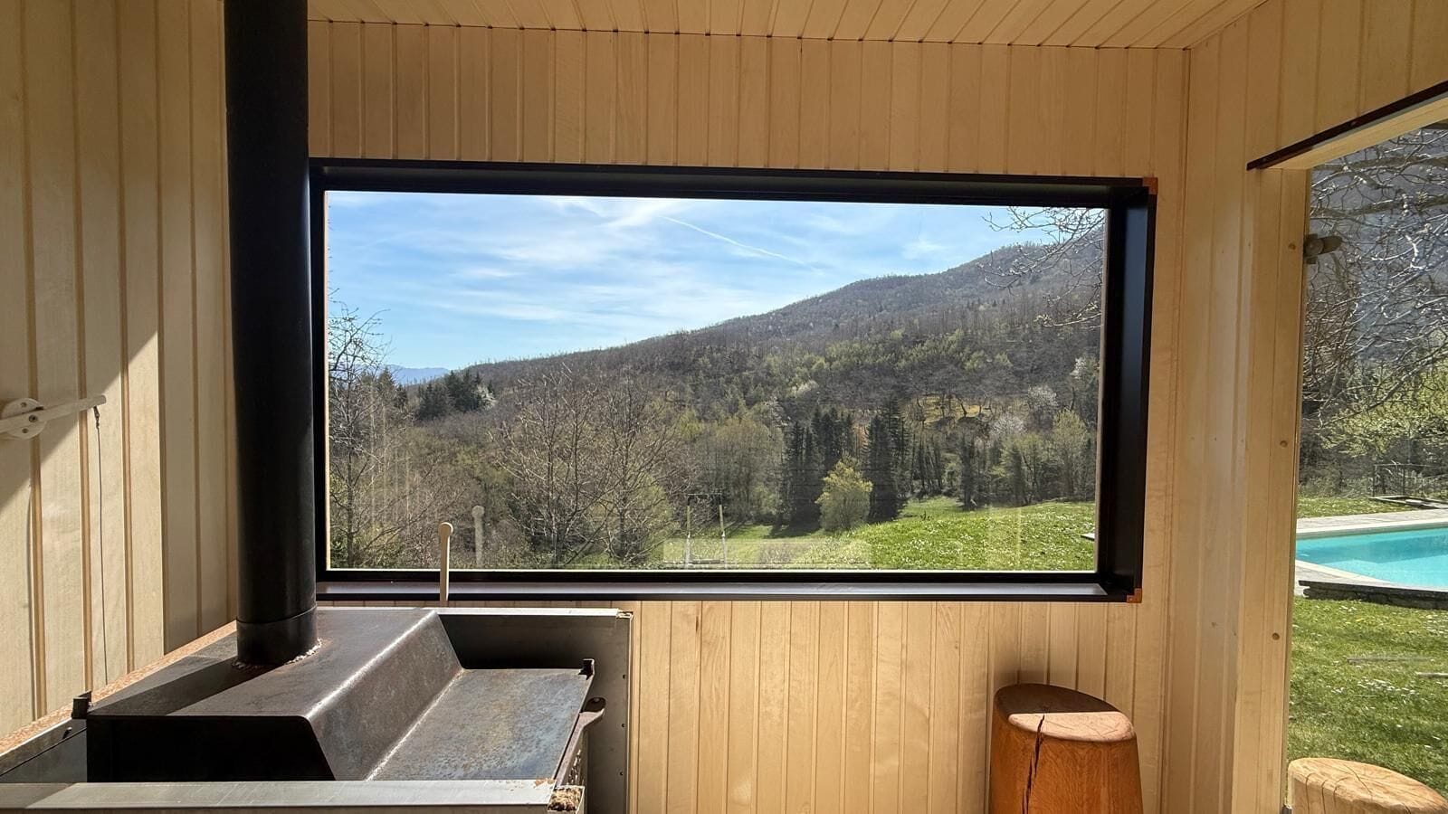 A wooden cabin with a large window overlooking a mountainous landscape.