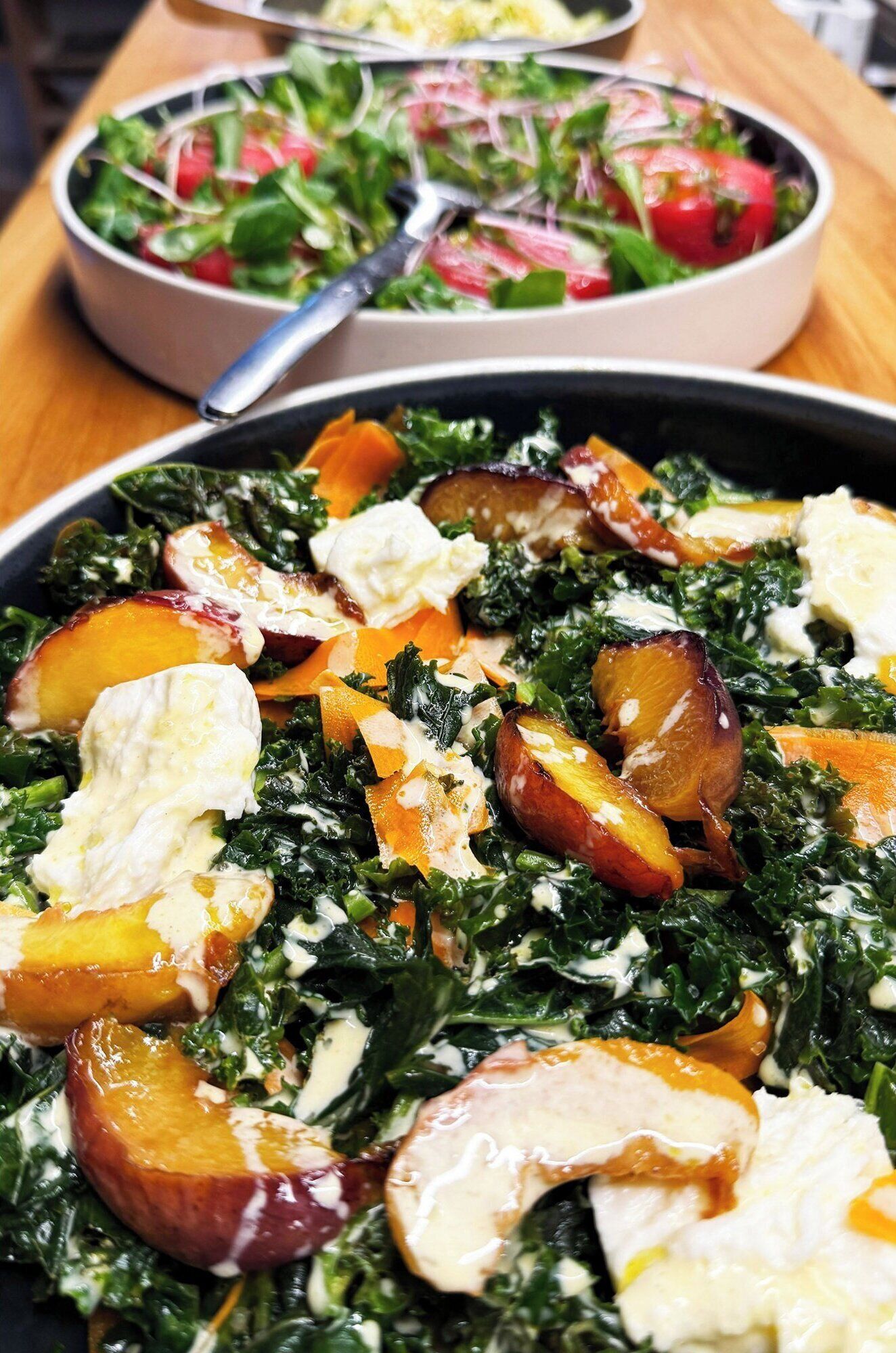 A salad with greens, fruits, and a creamy dressing.