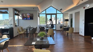 Un comedor moderno con ventanas amplias, un televisor de pantalla plana y vistas a la ciudad.