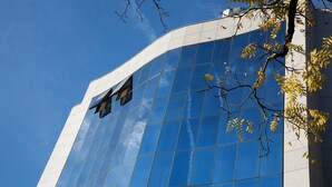 Un edificio moderno con fachada de vidrio reflectante y un elemento vertical blanco destacado.