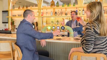 Zona de bar con mostrador, una variedad de botellas y una persona sirviendo una bebida.