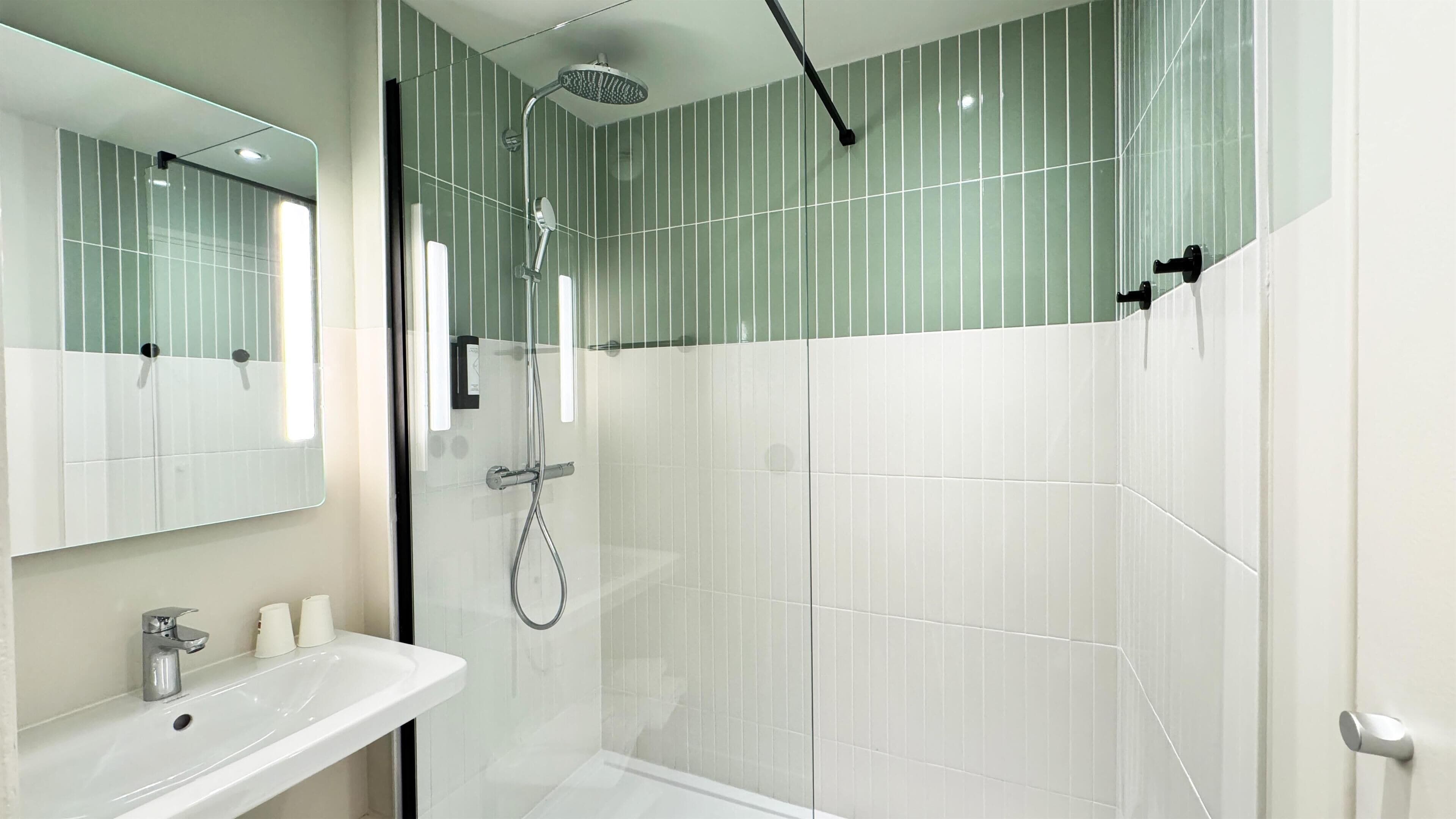 A modern bathroom with a glass shower enclosure, a white sink, and a large mirror.