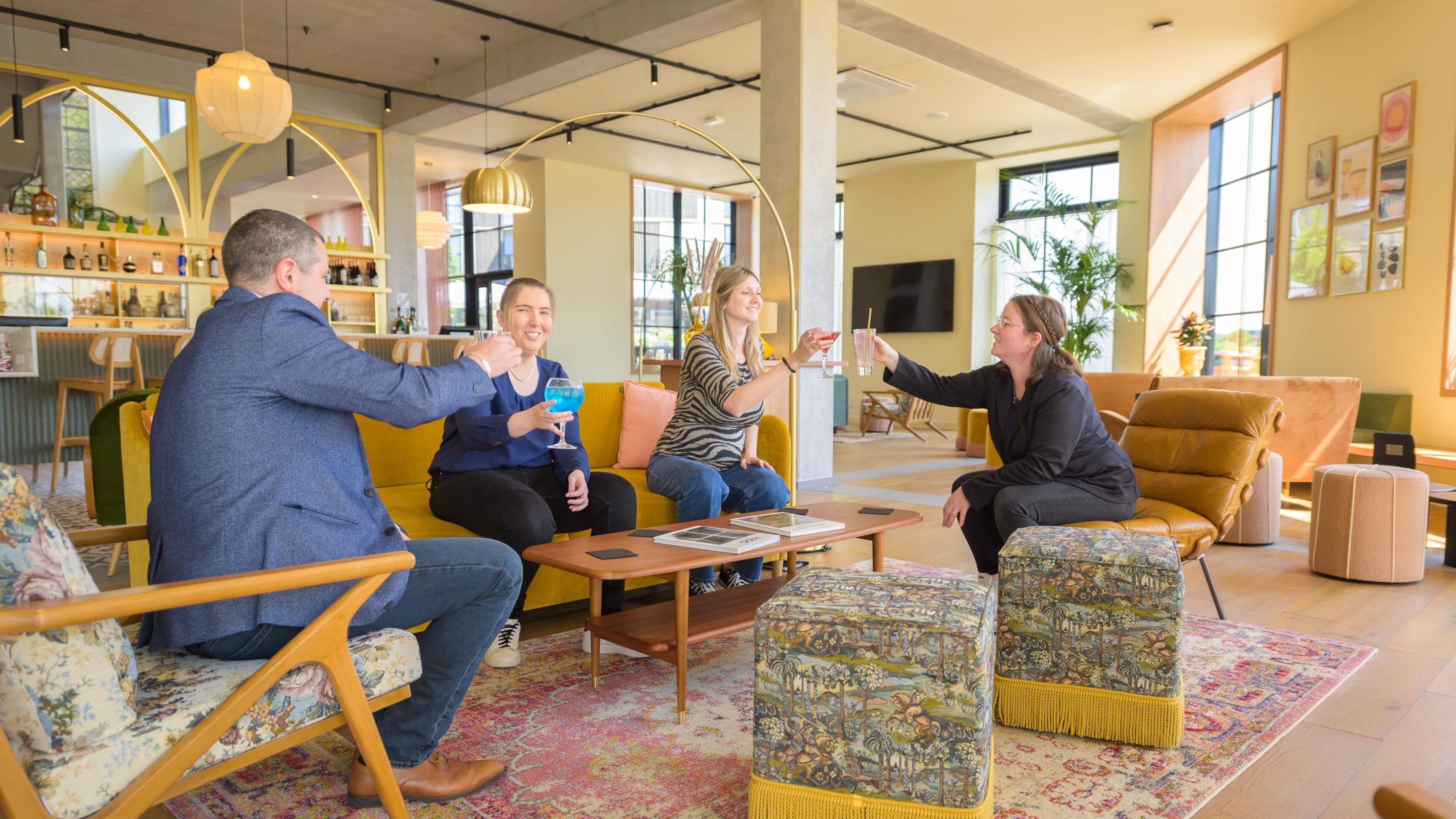 Een moderne lounge met zithoeken, een bar op de achtergrond en grote ramen voor natuurlijk licht.