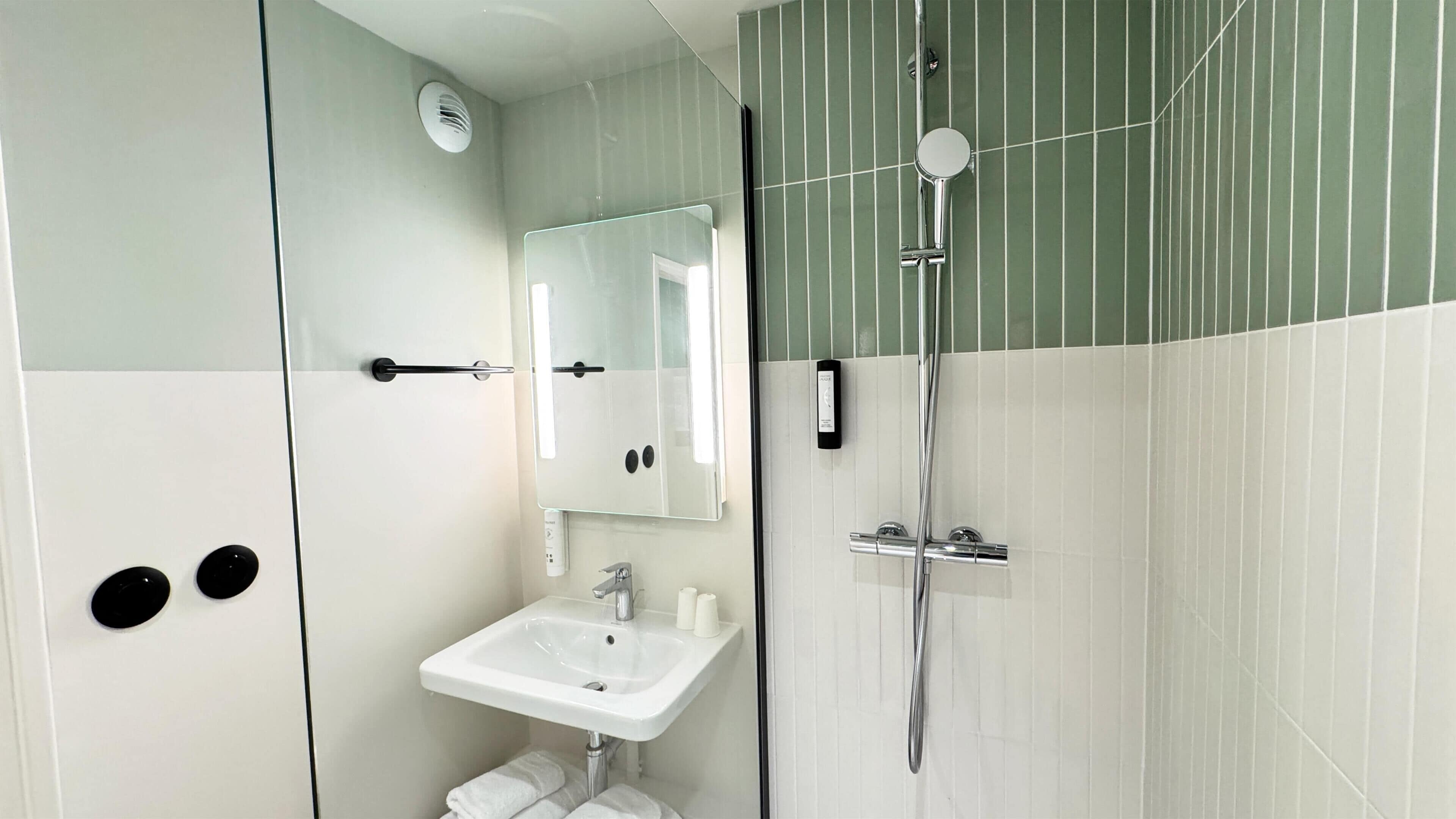 Un baño moderno con cabina de ducha de vidrio, un lavabo blanco y un espejo.