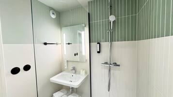 Un baño moderno con cabina de ducha de vidrio, un lavabo blanco y un espejo.