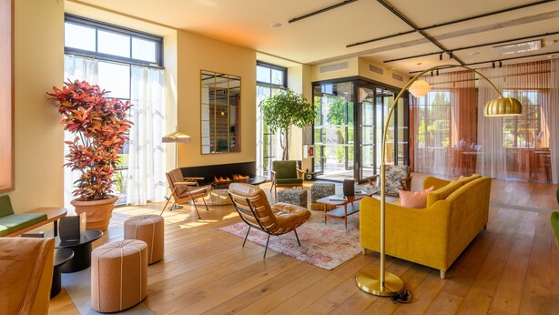 A spacious living room with a fireplace, comfortable seating, a large potted plant, and a view of the outdoors. - Kyriad Prestige Compiègne Hotel & Spa (Compiègne)