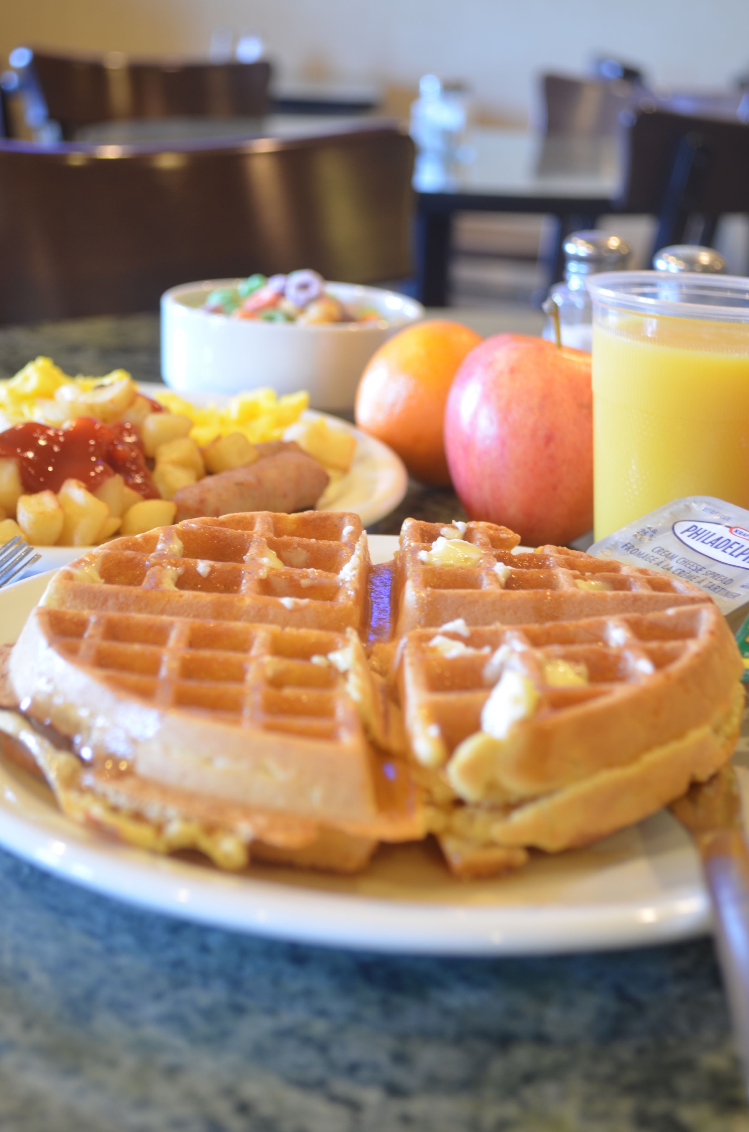 A breakfast plate with waffles, fruit, and a glass of orange juice.