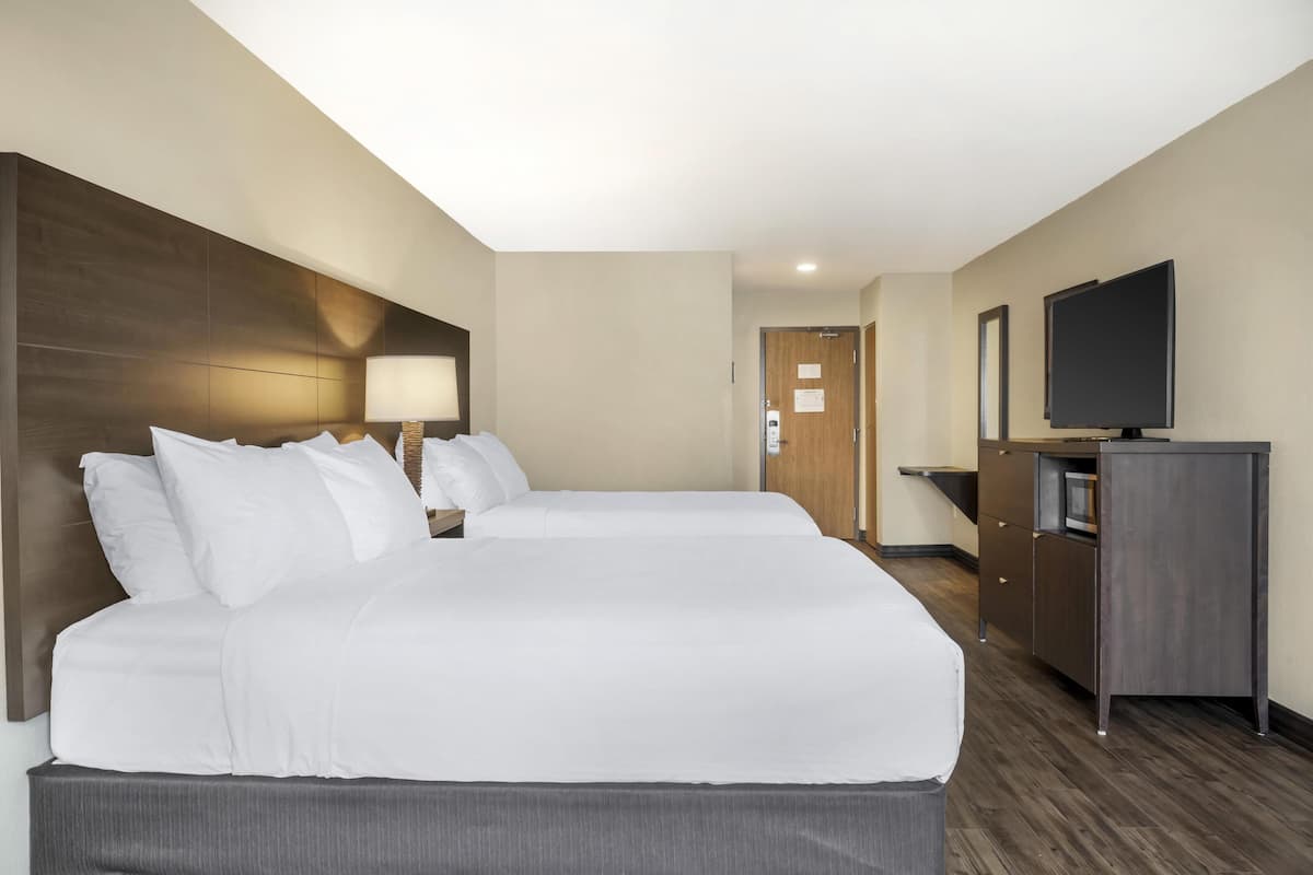 A hotel room with two beds, a TV, a desk, and a wardrobe.