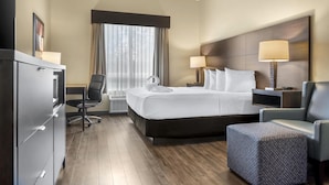Habitación de hotel con una cama grande, dos lámparas de noche, un escritorio con silla, un televisor y un armario.