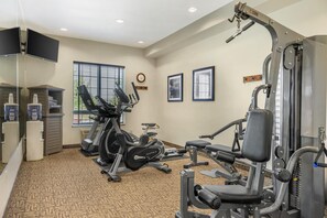 Un gimnasio con cintas de correr, máquinas de pesas y un dispensador de agua.