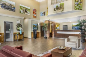 Un vestíbulo de hotel con mostrador de recepción, zona de estar y obras de arte en las paredes.