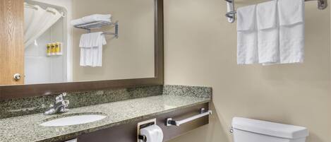 A bathroom with a granite countertop sink, a mirror, a towel rack, and a toilet.