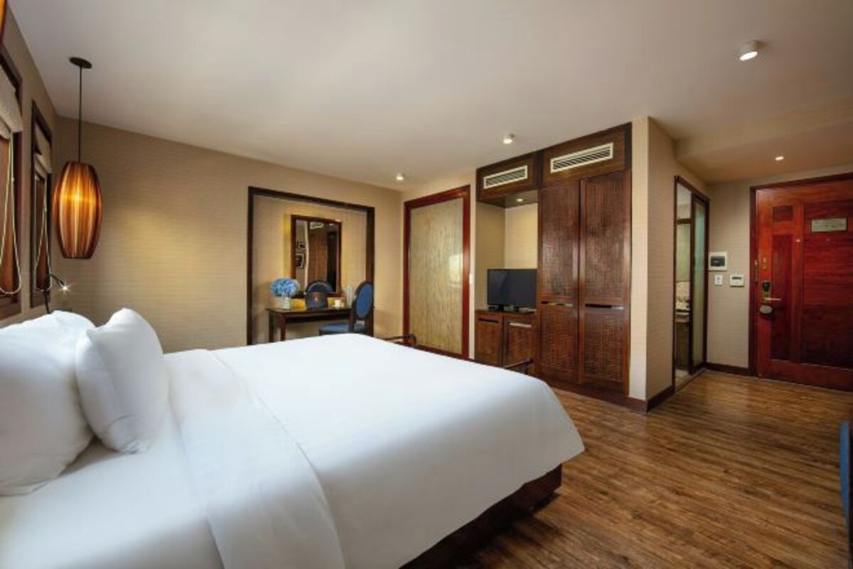 Une chambre d’hôtel avec un grand lit, un bureau avec une chaise, une télévision et une armoire.