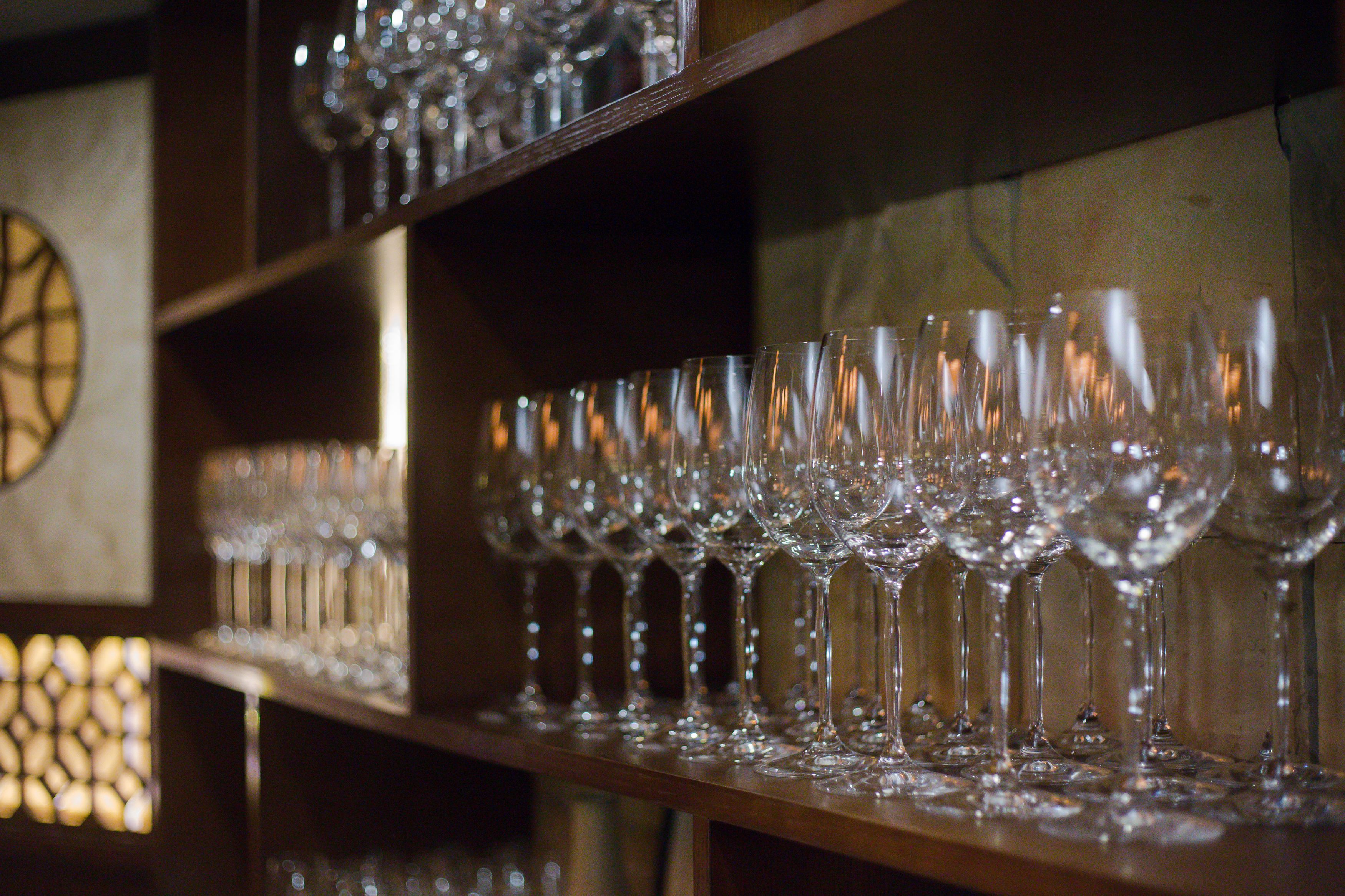 Una hilera de copas de vino vacías sobre estantes en una habitación tenuemente iluminada.