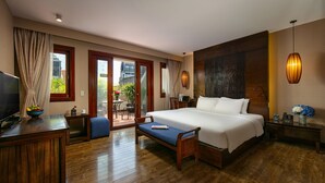 Une chambre d’hôtel avec un grand lit, un plancher en bois, une télévision, un bureau et une vue sur l’extérieur.