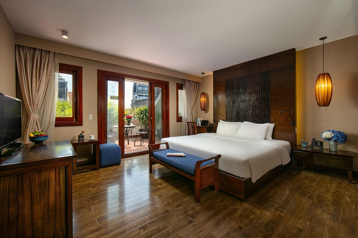 Une chambre d’hôtel avec un grand lit, un plancher en bois, une télévision, un bureau et une vue sur l’extérieur.