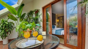 Une table ronde sur laquelle se trouvent un plateau de jus d’orange, une assiette avec une serviette et un verre avec une paille. Des plantes en pot sont disposées autour de la table.