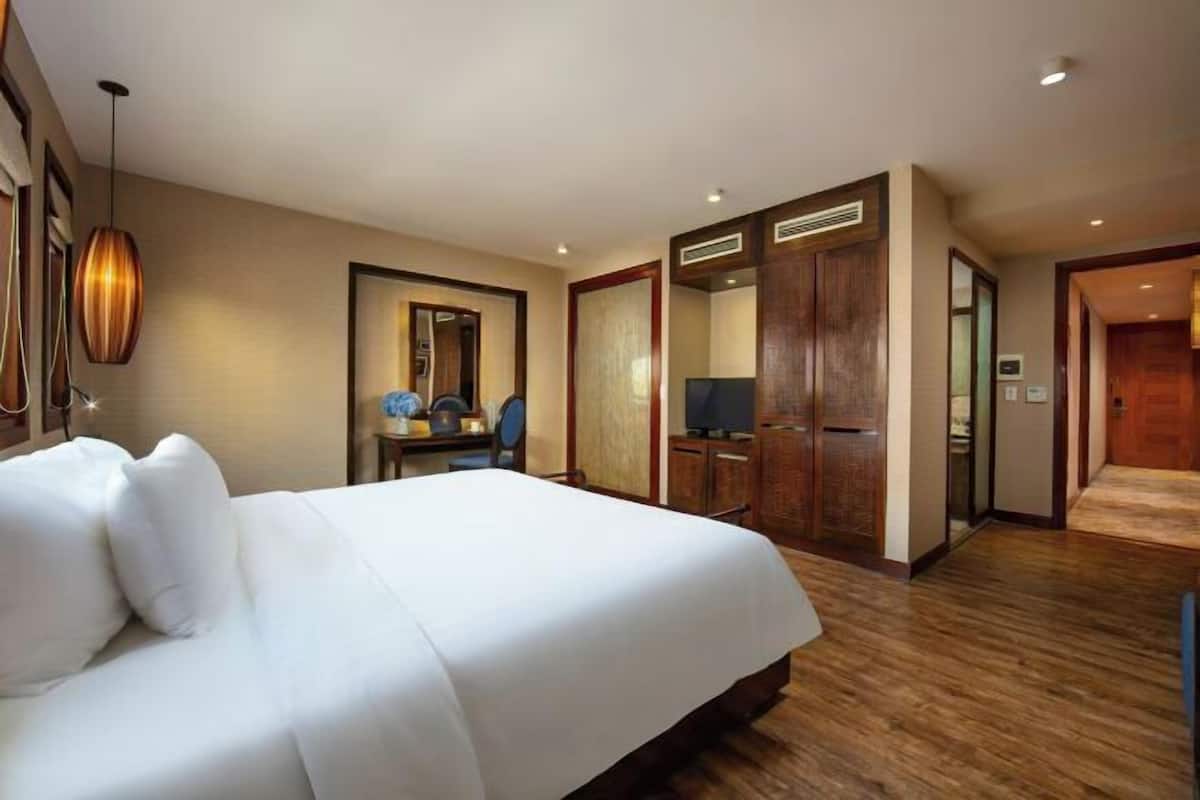 Une chambre d’hôtel avec un grand lit, un bureau avec une chaise, une télévision et une armoire.