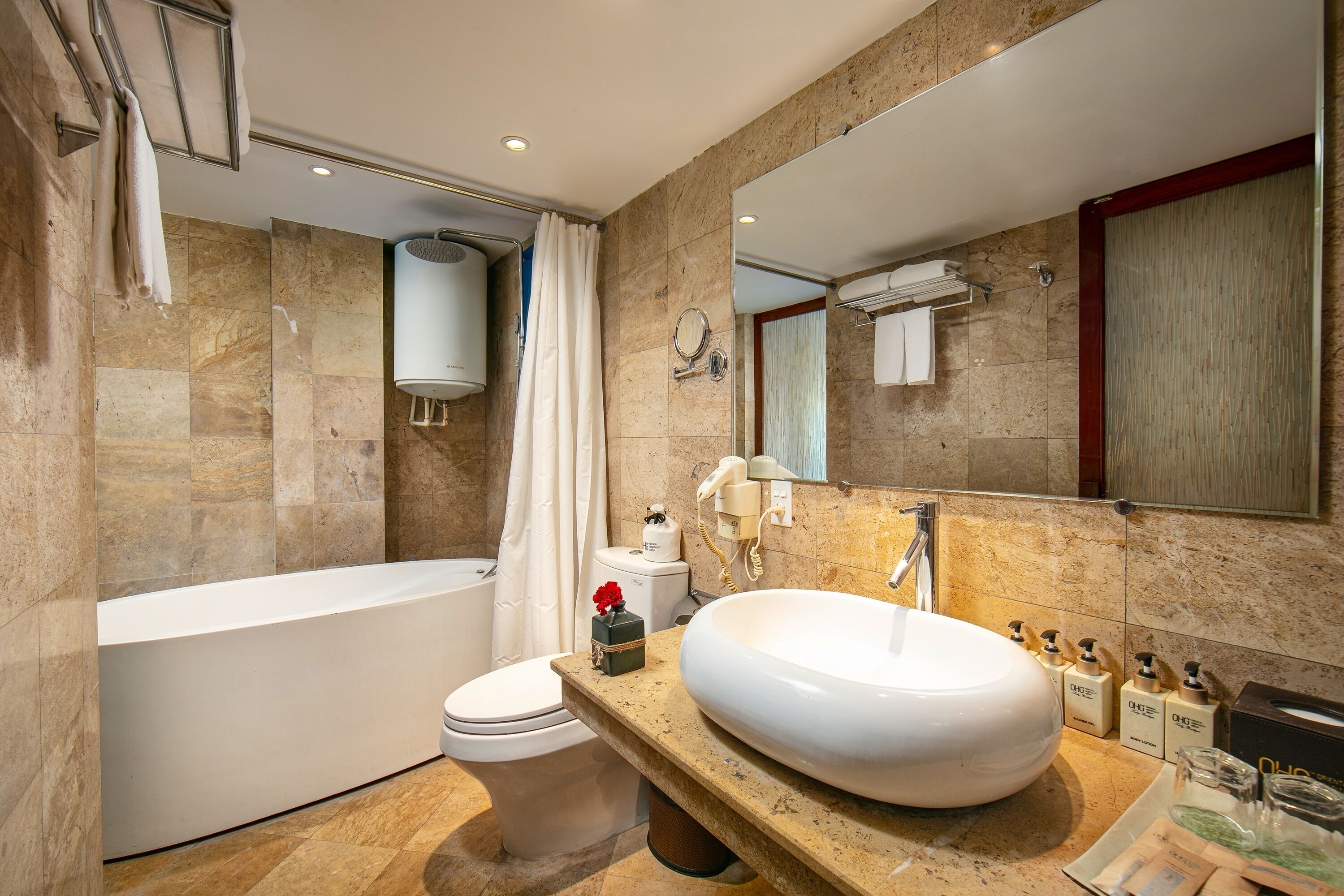 A modern bathroom with a large bathtub, a round sink, and a mirror above the sink.