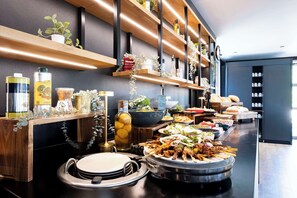 A buffet setup with various dishes, a sink, and shelves with items like bottles and plants. - Campanile Roissy - Aéroport CDG - Le Mesnil Amelot (Le Mesnil-Amelot)
