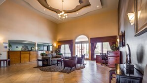 A spacious lobby with a reception desk, seating area, and a large window with curtains. - Best Western Plus Main Street Inn (Brawley)