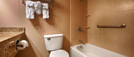 Un baño con inodoro, bañera y toallero con toallas.