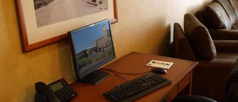 Ein Hotelzimmer mit einem Holztisch, einem Computer, einem Telefon und einem gerahmten Bild von Wölfen an der Wand.