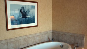 Un baño moderno con una bañera independiente, paredes con azulejos y un cuadro enmarcado de un águila.