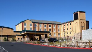 Un hotel de varios pisos con techo plano, entrada cubierta y fachada de piedra.