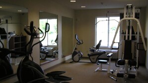 Un gimnasio con equipo de ejercicio, incluyendo cintas de correr, bicicletas estáticas y máquinas de pesas.