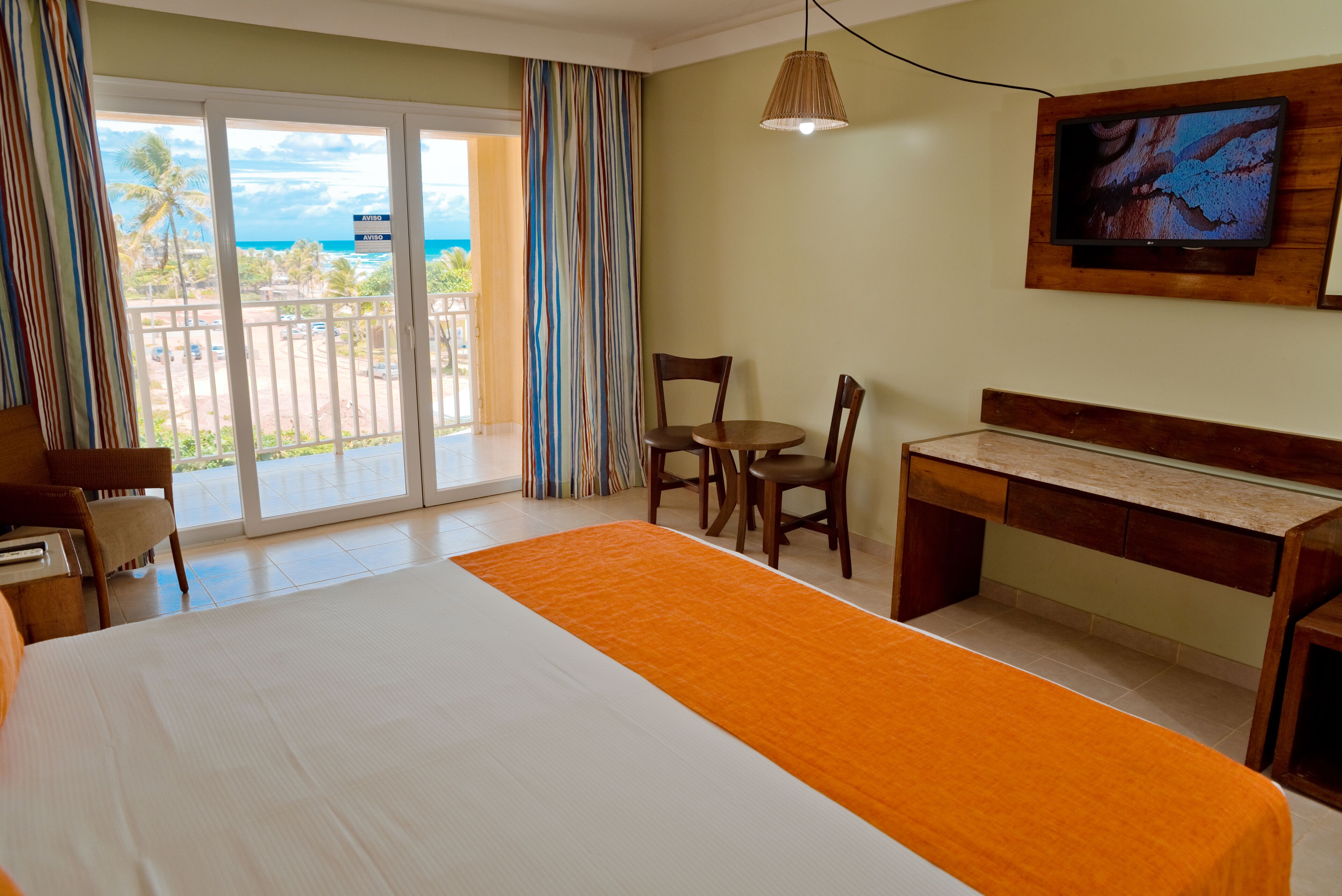 A hotel room with a bed, a desk, a chair, and a television.
