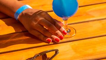Una persona sentada a una mesa de madera con una bebida azul en un vaso.