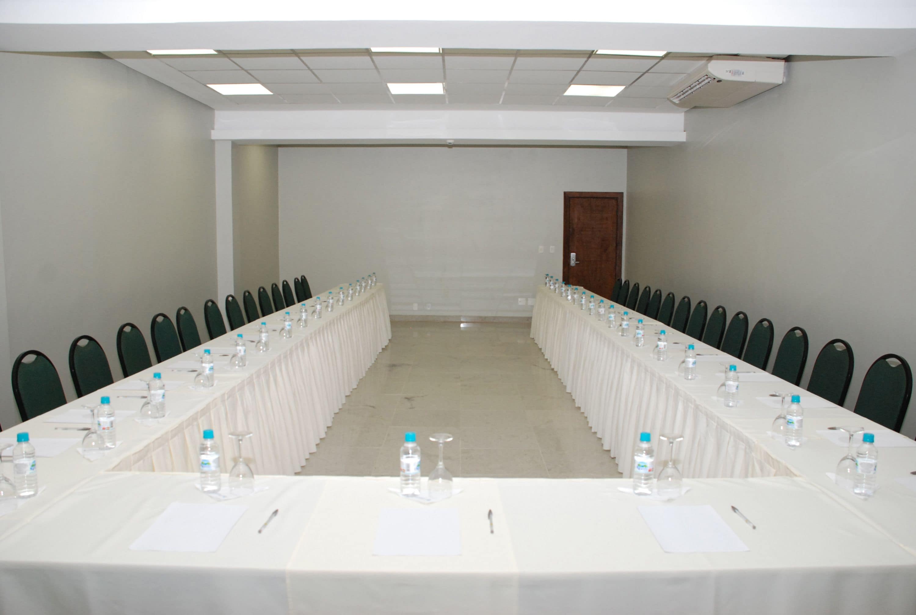 A conference room with a long table, chairs, water bottles, and documents.