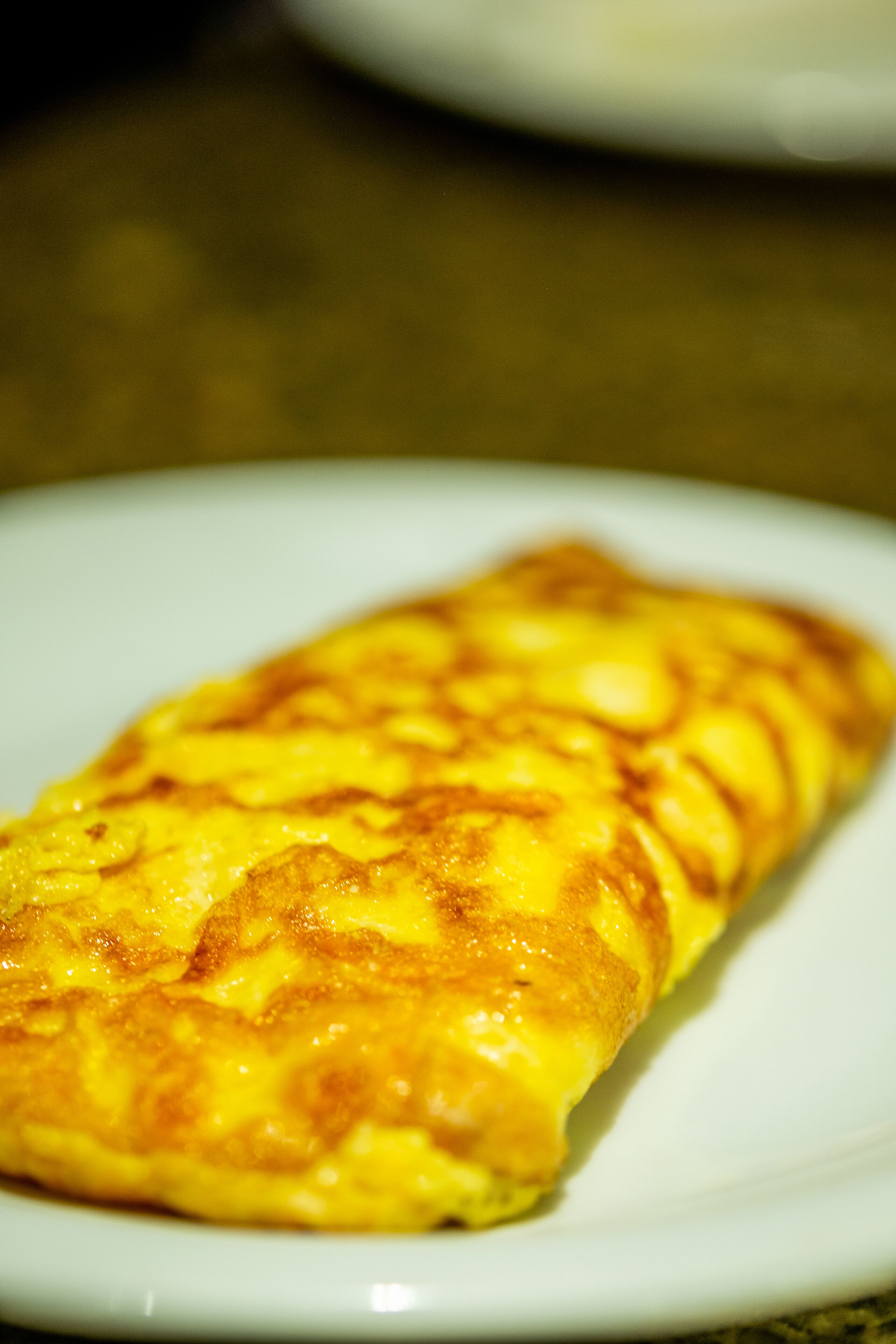 A close-up of a folded omelette on a white plate.