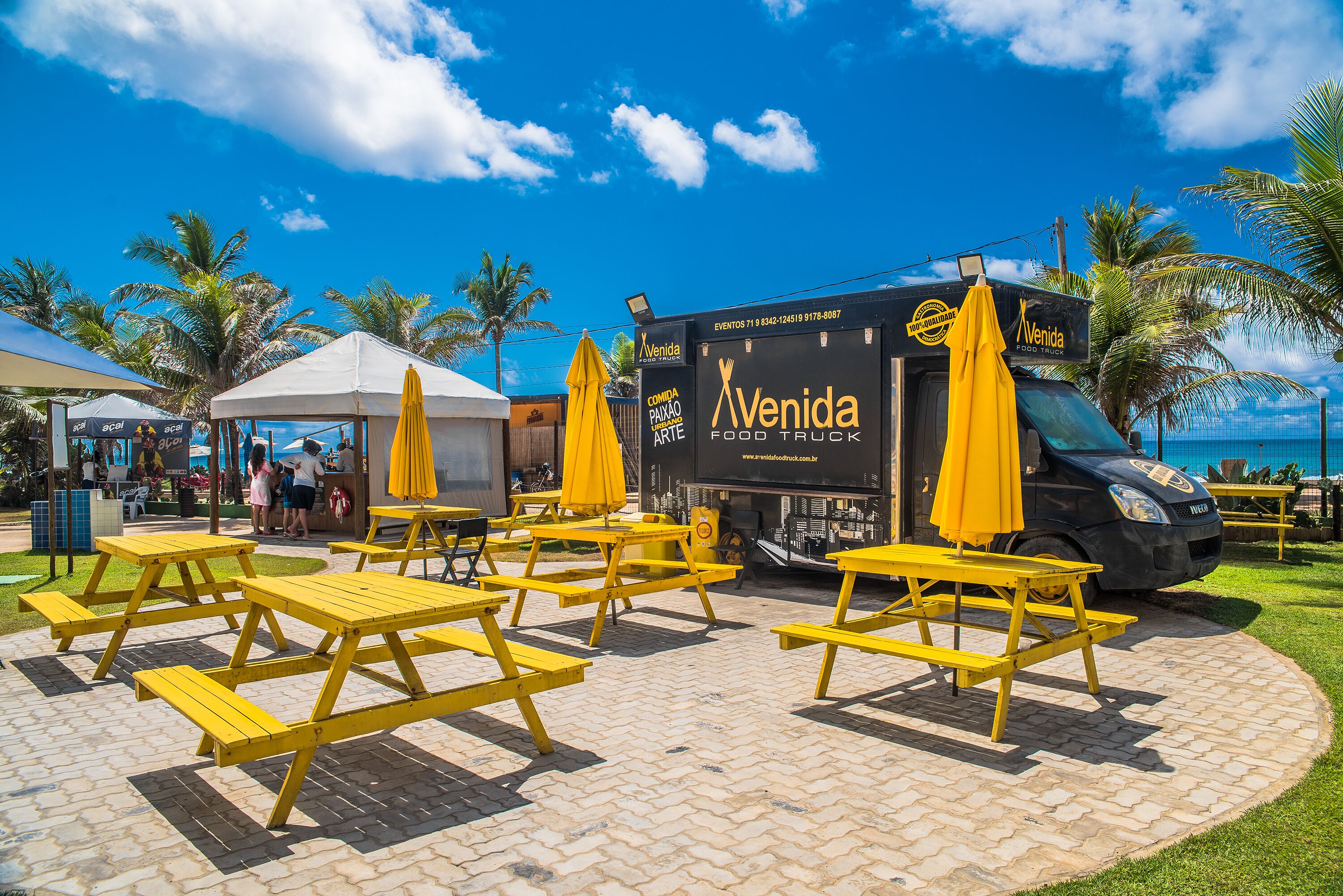 A food truck with yellow umbrellas and a picnic table area.