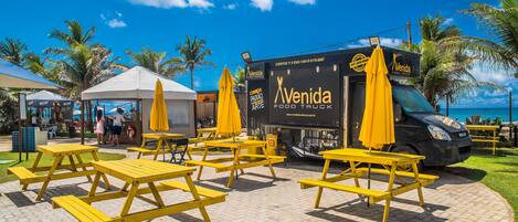 A food truck with yellow umbrellas and a picnic table area.