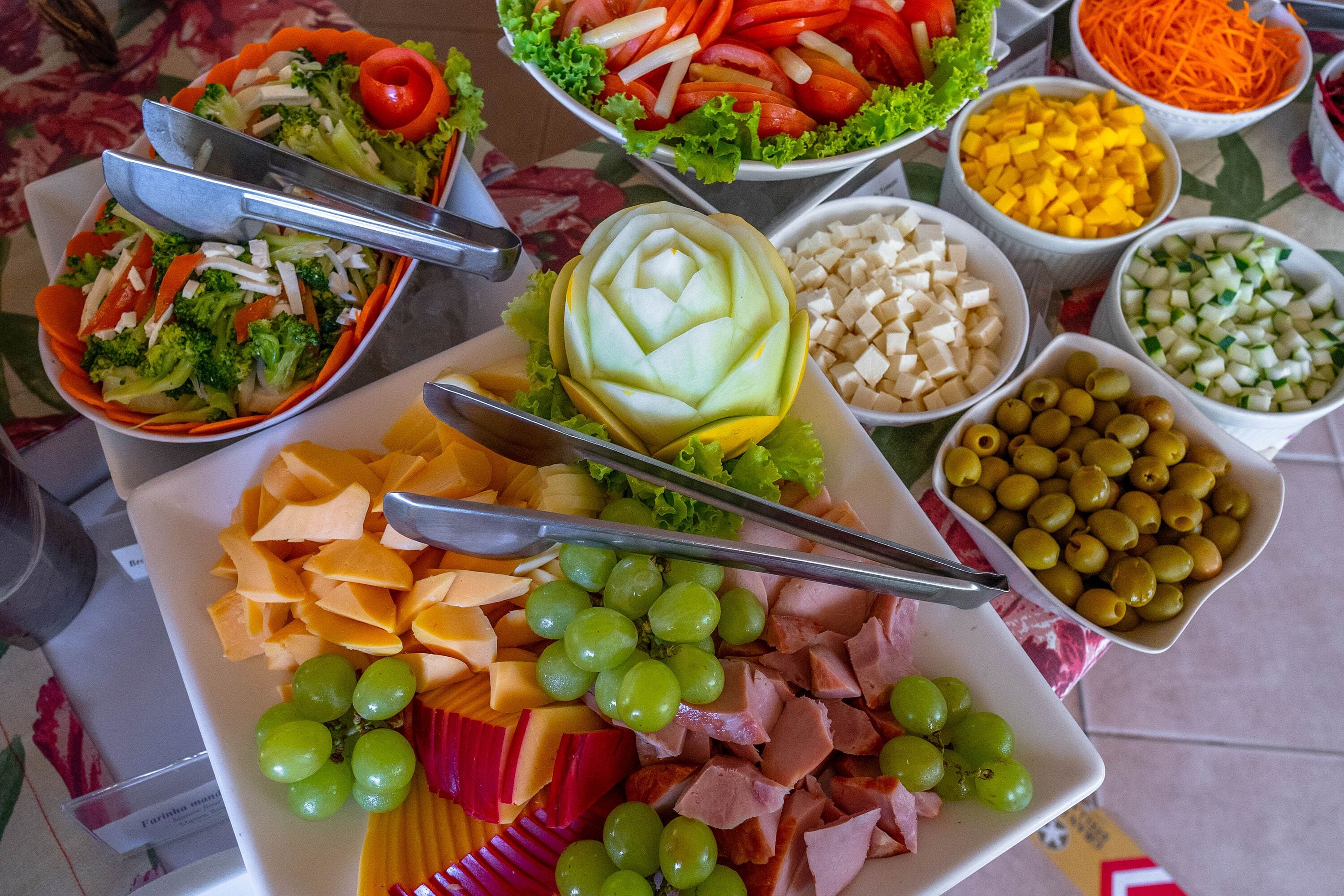 A variety of food items including cheese, ham, grapes, and vegetables arranged on a table.
