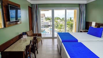 Habitación de hotel con balcón, cama, escritorio y televisor.