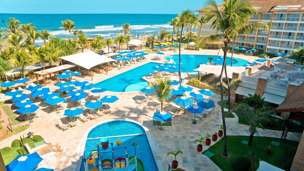Un espace piscine d’un complexe hôtelier comprenant plusieurs piscines, des chaises longues et des parasols.