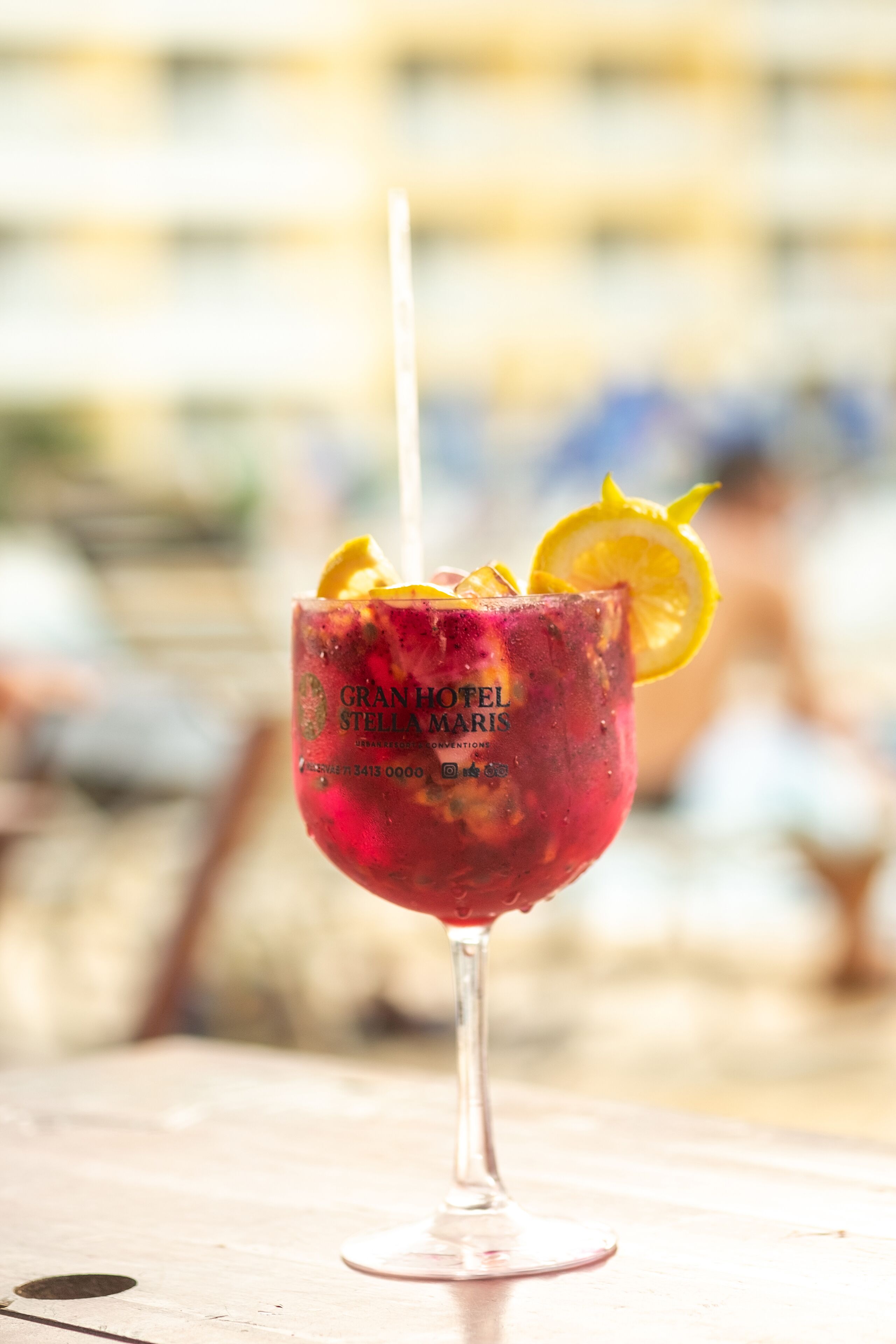 Ein Cocktailglas mit Strohhalm, garniert mit einer Zitronenscheibe, auf einem Holztisch.