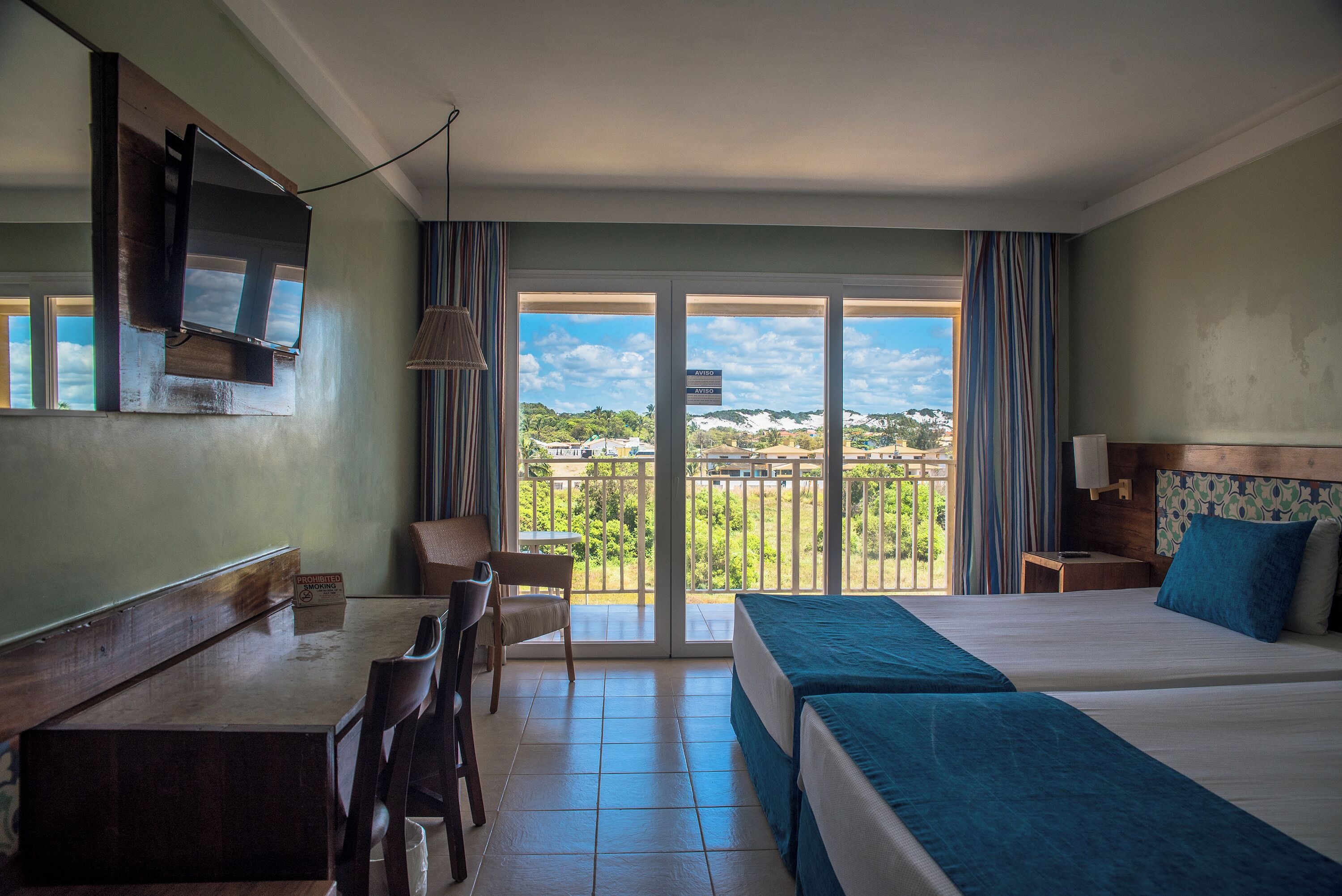 A hotel room with a balcony, a desk, and a bed.