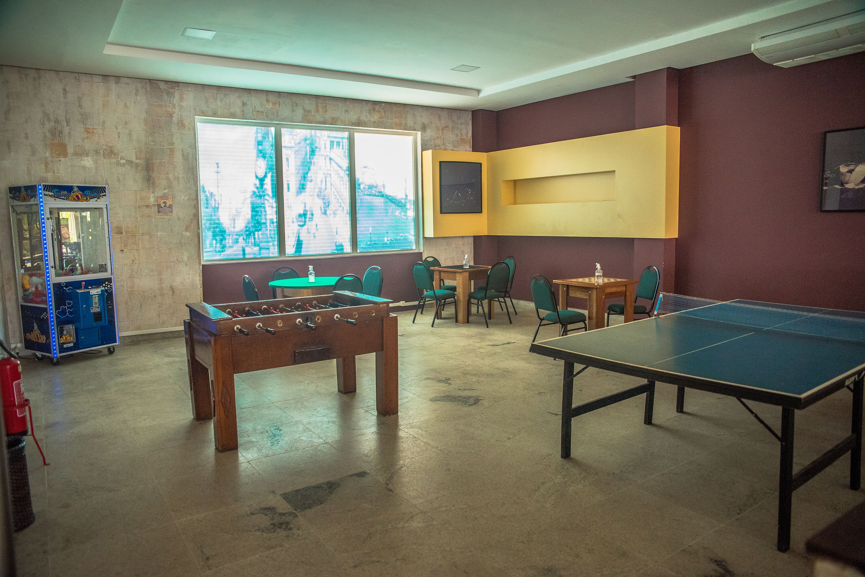 Una habitación con mesa de fútbol de mesa, mesa de ping pong y otra mesa de fútbol en la esquina.